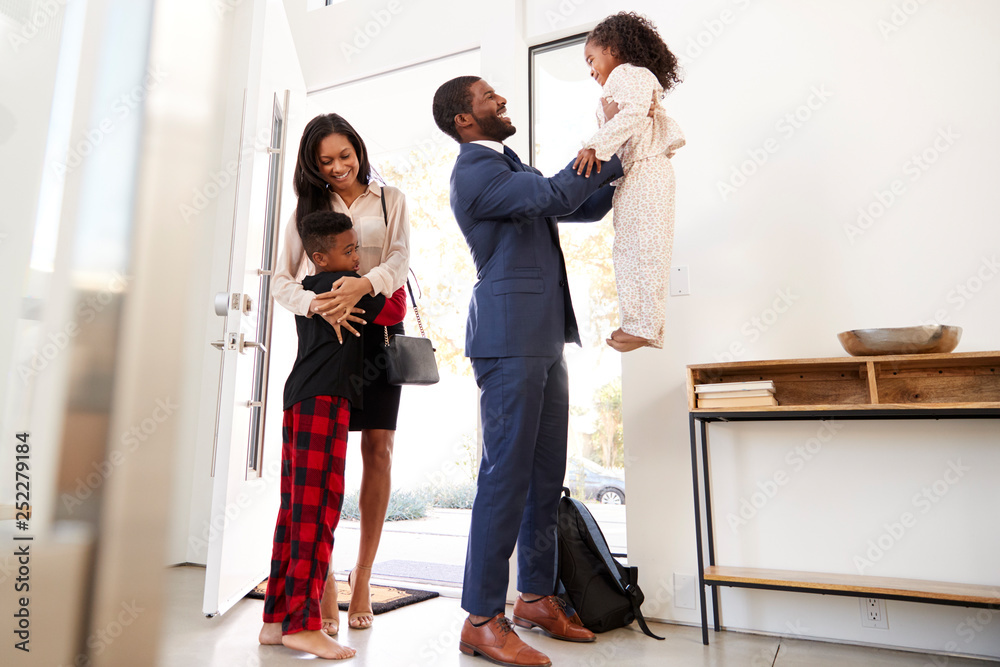 Fototapeta premium Children Greeting And Hugging Working Parents As They Return Home From Work