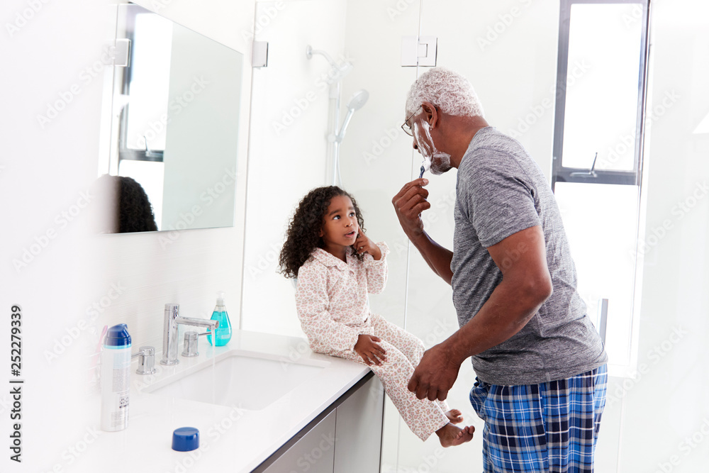 Obraz premium Grandfather Wearing Pajamas In Bathroom Shaving Whilst Granddaughter Watches