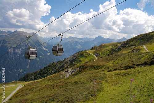 Aerial cable car view hanging over green Austrian Alps in summer with sky background