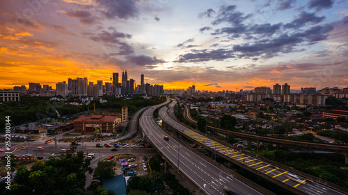 Kuala Lumpur city skyline during dramatic sunset with elevated highway leading into the city. © nurismailmoham