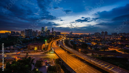 Kuala Lumpur city skyline during dramatic sunset with elevated highway leading into the city.