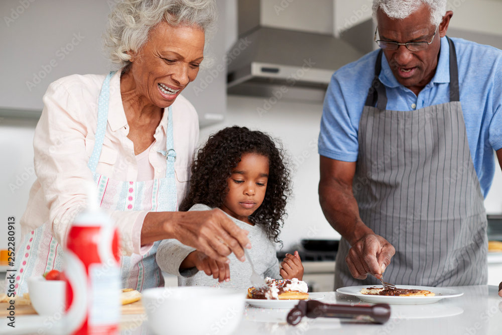 Grandparents In Kitchen With Granddaughter Making Pancakes Together Grandparents In Kitchen With Granddaughter Making Pancakes Together