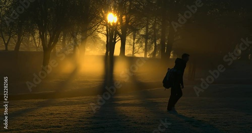 A Golfer walks between holes at sunrise.