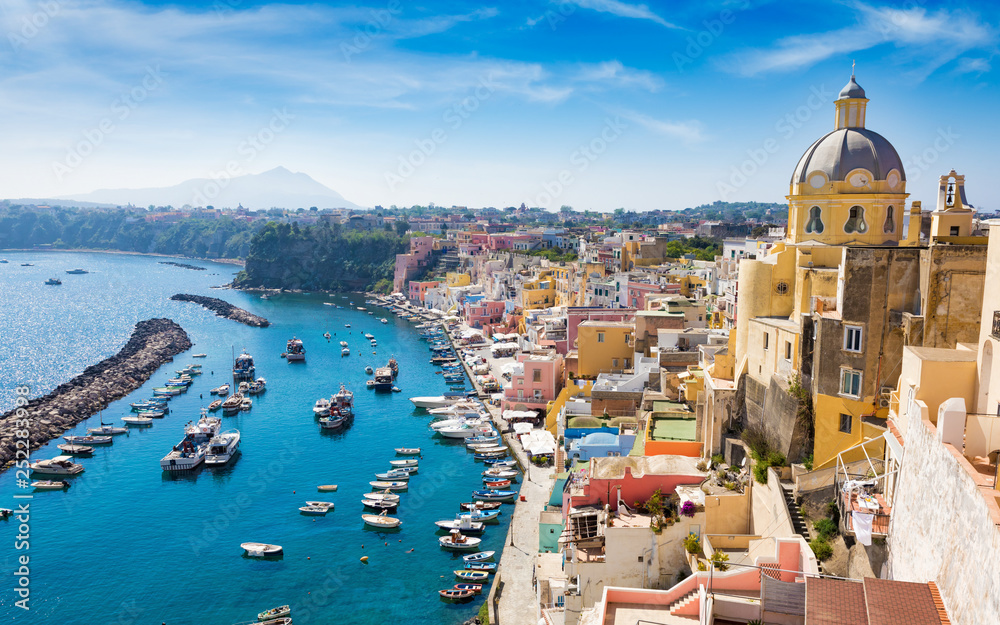 Colorful housing, fishing boats and yachts, cafes and restaurants in Marina Corricella, Procida island, Italy