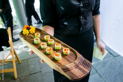 Slika na platnu a waiter holding a wooden platter full of vegetarian appetizers - wedding cateri
