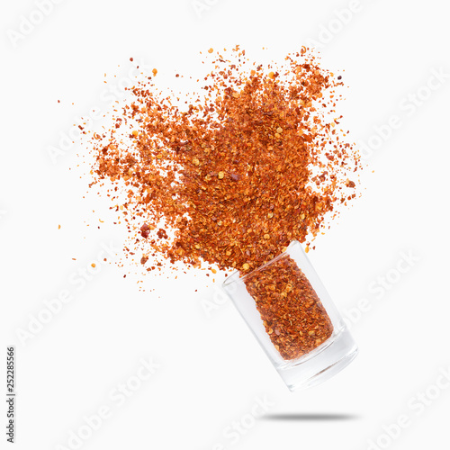 Glass jar with chili pepper flying on white background photo