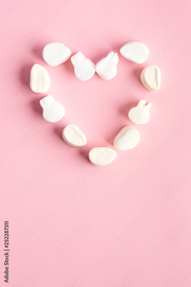 Fototapeta premium Sugar clouds making the shape of a heart on pink background
