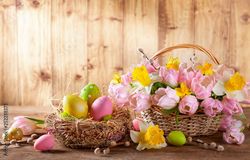 Easter holiday basket with beautiful spring flowers and nest with Easter eggs.