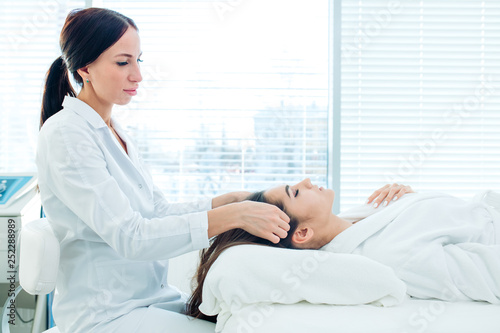 Cosmetology image of beautician doing head massage or prepare female patient to hardware cosmetology procedures. Beauty concept. Cosmetology concept. Cosmetology salon.