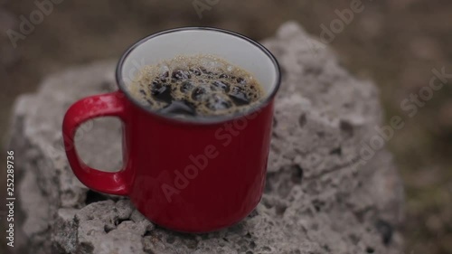 Red cup of coffee on the stone.
