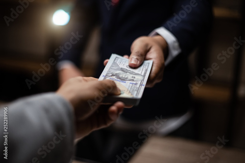 Businessman giving bribe money  to partner in a corruption scam with black  tone,corruption