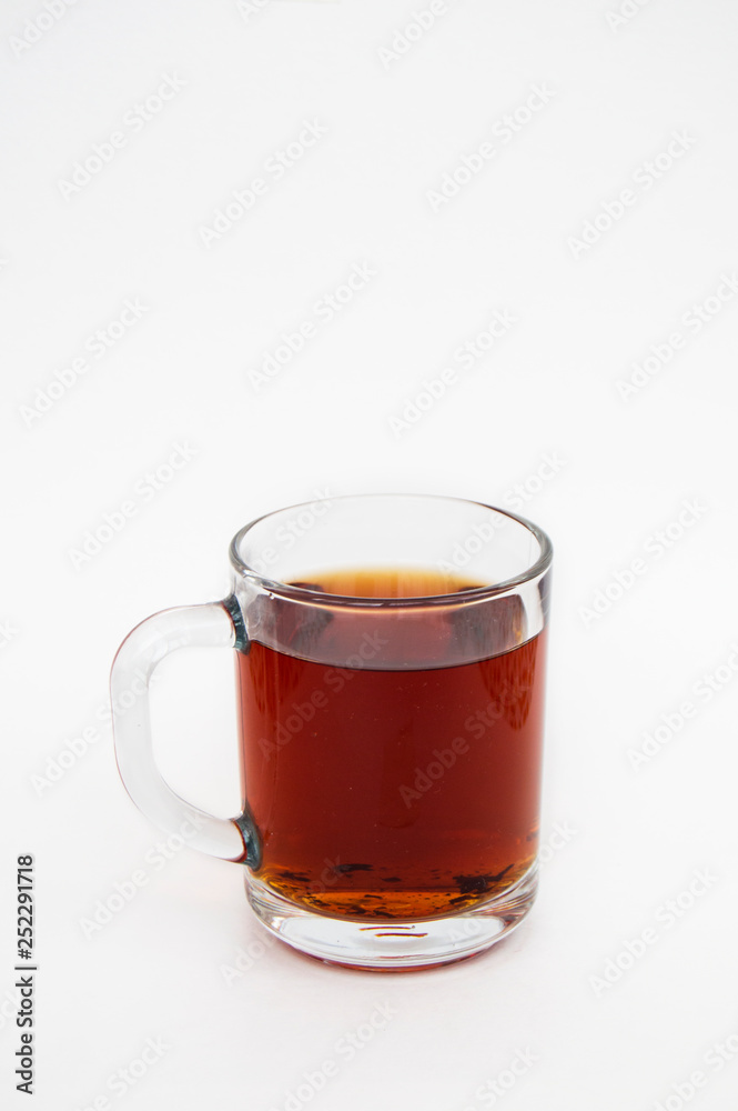 Delicious black tea in a transparent mug on a white background. Vertical photo Delicious black tea in a transparent mug on a white background. Vertical photo