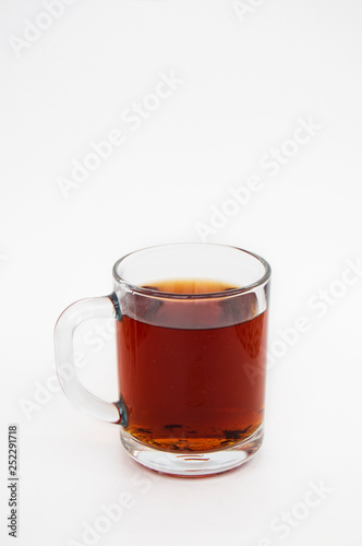 Delicious black tea in a transparent mug on a white background. Vertical photo