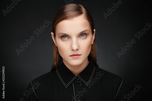 Close-up portrait of a beautiful model with clean makeup and collected hair, photographed in a photo studio