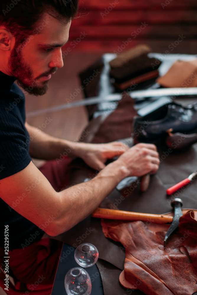 handsome worker of shoemaking industry.close up cropped photo. man cutting material into shape handsome worker of shoemaking industry.close up cropped photo. man cutting material into shape