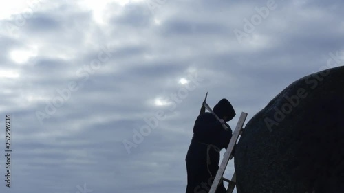 man in black hoodie with pickaxe climbing to rock silhouette photo