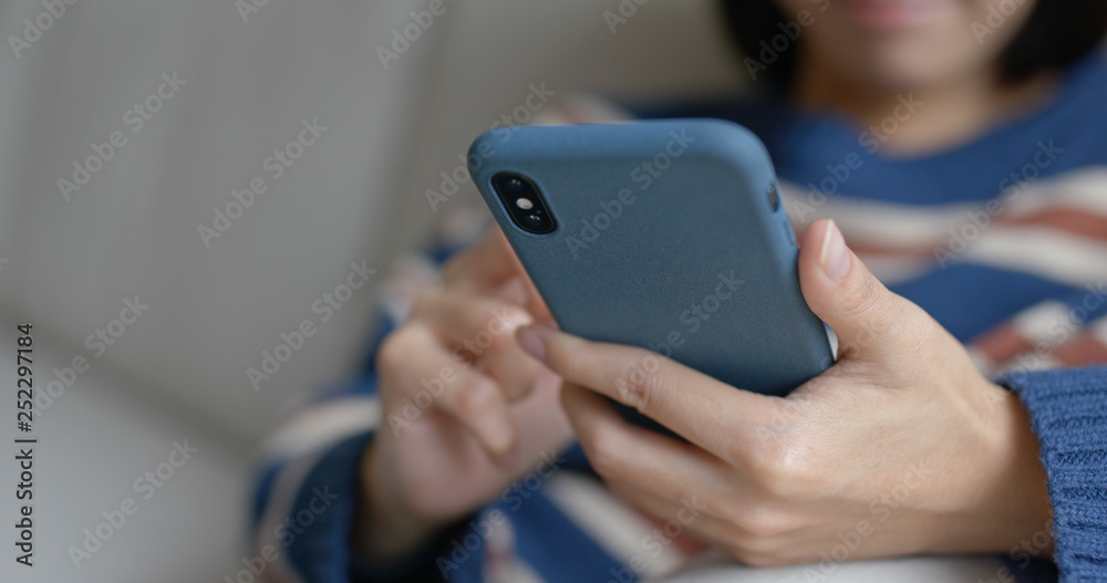 Woman use of mobile phone and sit on sofa at home