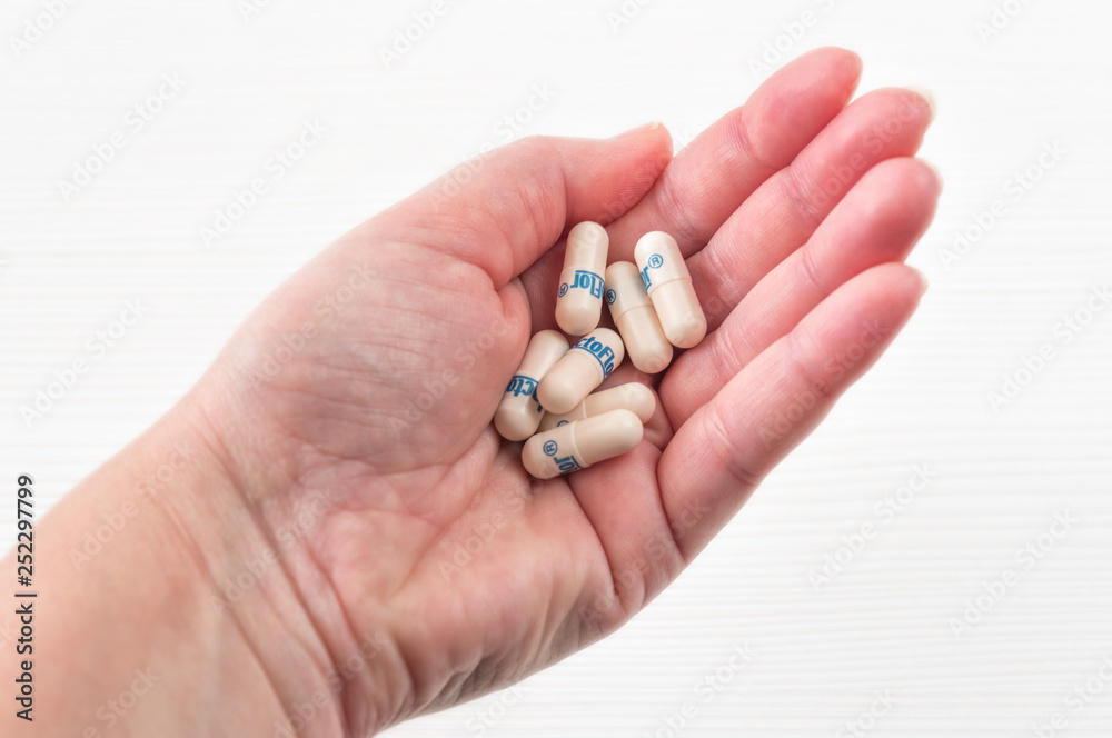 Female hand holding many colorful pills, capsules, tablets on white wooden background.Taking Your Medication.Top view. Female hand holding many colorful pills, capsules, tablets on white wooden background.Taking Your Medication.Top view.