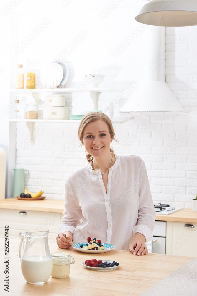 happy young woman preparing tasty snacks at the kitchen table in the morning light happy young woman preparing tasty snacks at the kitchen table in the morning light