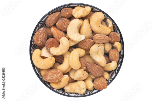 Nuts background. Close-up of roasted and salted almonds and cashew nuts in a ceramic bowl isolated on a white background. Gourmet nut mix with almonds. Macro. Top view.