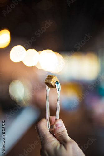 A piece of sweet, cane sugar raffinate in pinch coffins on a cafe background. Concept for service restaurant business. selective focus, noise effect