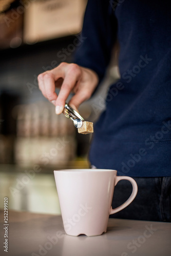 A piece of sweet, cane sugar raffinate in pinch coffins on a cafe  background. Concept for service restaurant business. selective focus, noise effect photo