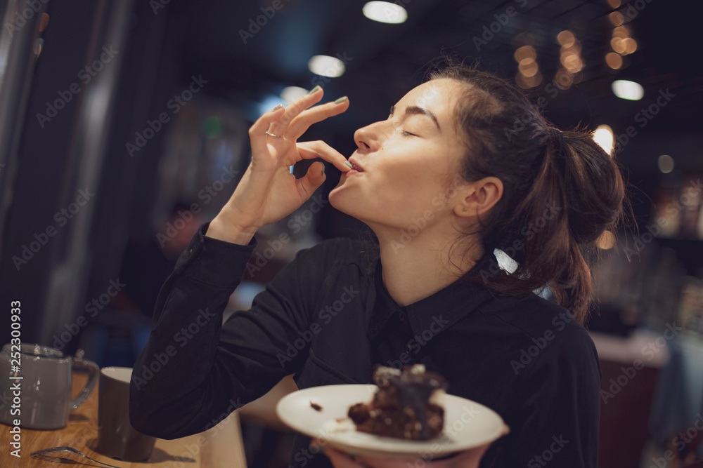 Picture of cheerful girl in cafe, eating piece of cake, selective focus, noise effect