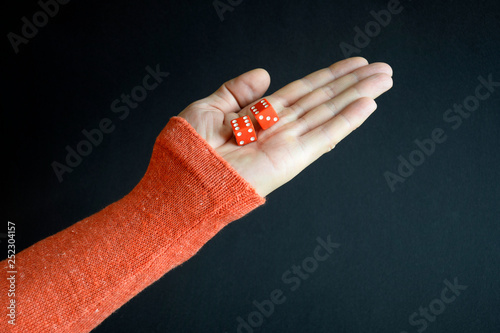 Foto Red playing dices in a male hand pointing up on black background, closeup, selective focus