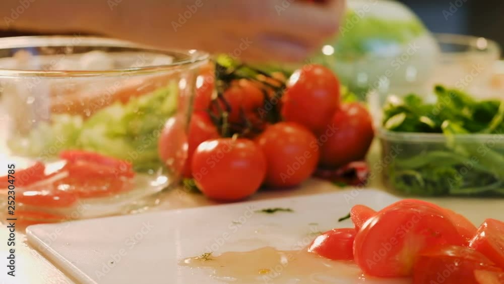 Salad preparing. Cooking healthy food. Woman putting sliced tomatoes in a bowl Salad preparing. Cooking healthy food. Woman putting sliced tomatoes in a bowl