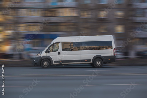 Minibus moves along the road in the city