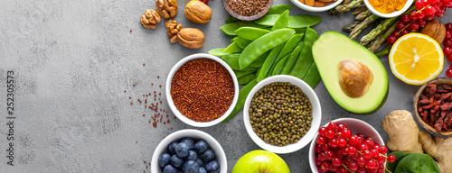 Healthy food background, spinach, quinoa, apple, blueberry, asparagus, turmeric, red currant, broccoli, mung bean, walnuts, grapefruit, ginger, avocado, almond, lemon  and green peas, top view, banner