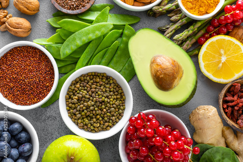 Healthy food background, spinach, quinoa, apple, blueberry, asparagus, turmeric, red currant, broccoli, mung bean, walnuts, grapefruit, ginger, avocado, almond, lemon, green peas and goji, top view