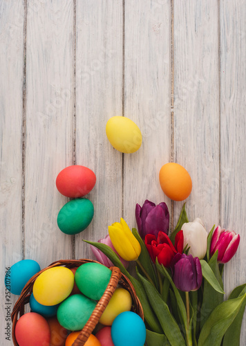 Colorful easter eggs,spring tulips on wooden texture background.On a white wood table,colored eggs,colors flowers.Happy religious day,traditional for people. Top view.Copy space.