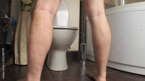 man pisses standing in the toilet in the bathroom.