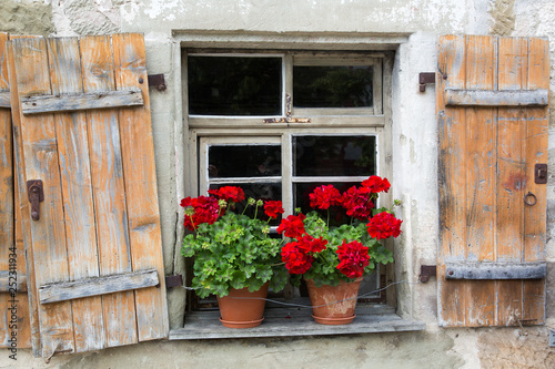 Altes Fenster mit offenen Holzfensterl  den und Blumenk  sten mit Geranien