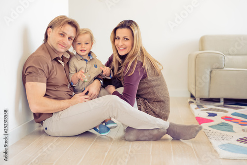 Happy family sitting on floor with their little baby. Family spending time at home with their son.