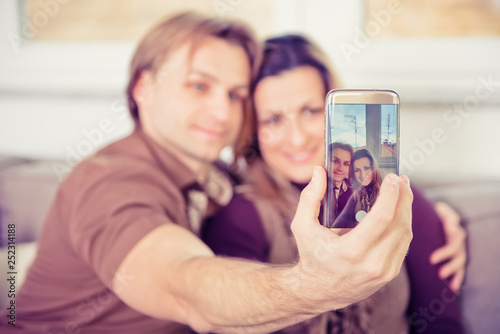 Happy young couple sitting on the sofa and doing selfie