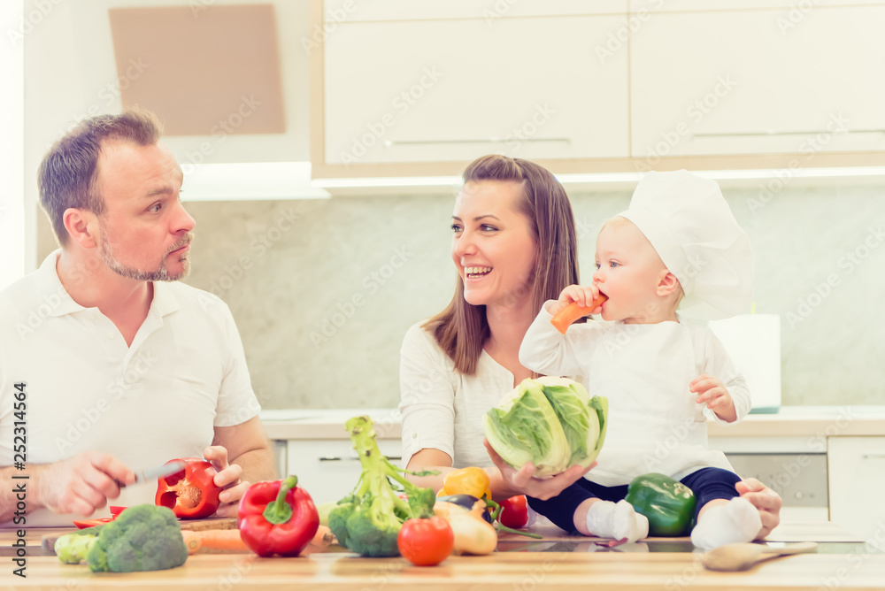 Happy parents sitting in the kitchen and prepares for cooking with their baby girl chef.