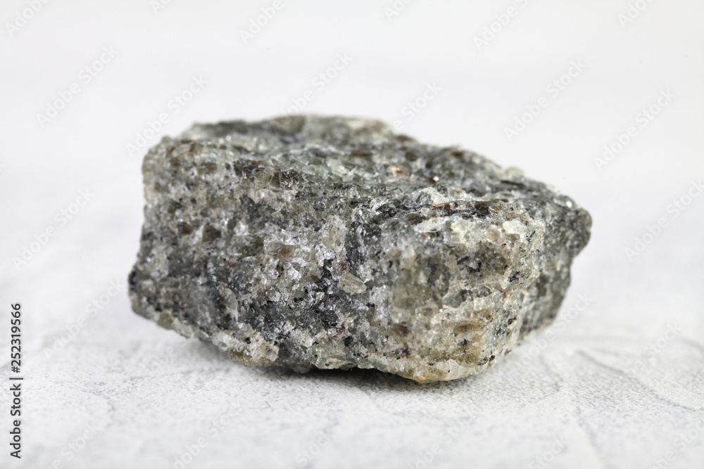 Obraz premium Natural mineral from geological collection - raw apatite, phosphorus ore stone from Khibiny, Kola Peninsula, Russia on white cement background.