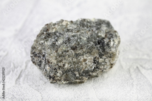 Natural mineral from geological collection - raw apatite, phosphorus ore stone from Khibiny, Kola Peninsula, Russia on white cement background. photo