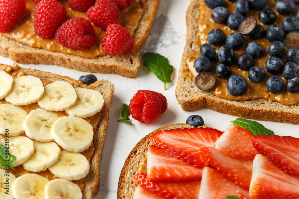Peanut butter sandwiches with fresh strawberry, blueberry, raspberry and banana whole meal toasts.