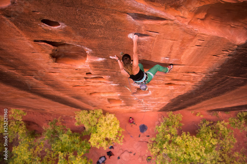 Athletic Woman climbing on overhanging cliff rock in fall photo