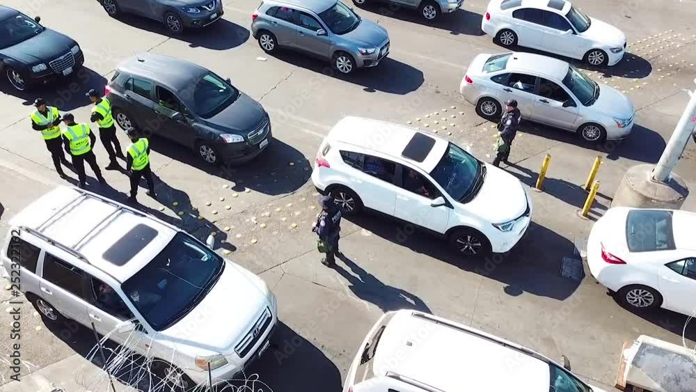 2018 - Border Patrol agents wait to inspect a line of cars at the San Ysidro Tijuana US Mexico border crossing.
