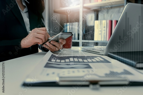 woman working on smart phone and laptop in office