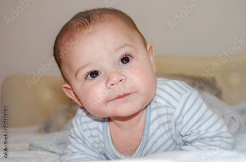 cute 4 months old baby boy having tummy time and making funny faces
