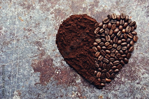 Coffee beans and ground coffee laid  out as a heart shape. Coffee cups and coffee beans isolated on vintage backgrond