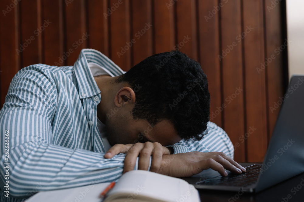 Tired and frustrated man sleeping at laptop computer, he working hard, burnout and stress at workplace. Overtime job concept. Freelancer missed deadline, feeling exhausted. 