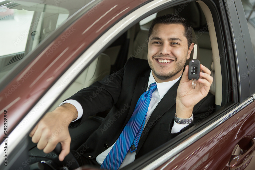 Happy male car owner showing keys to his new auto