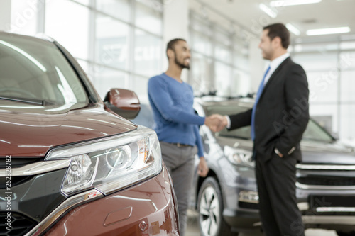 Handsome African man shaking hands with car dealer after buying an auto © Zoriana