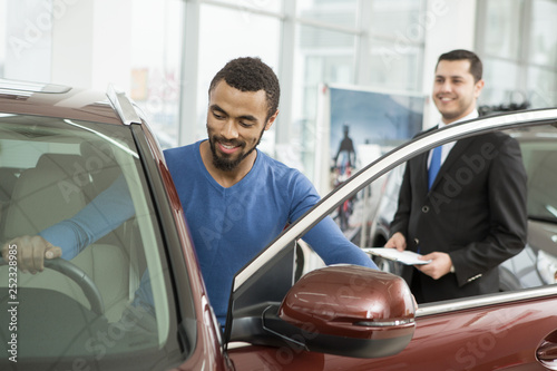 Young African man buying a car from a professional salesman